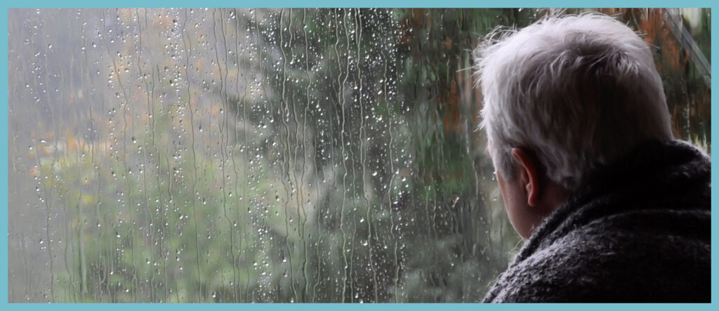 مردی پشت پنجره بارانی ایستاده است .